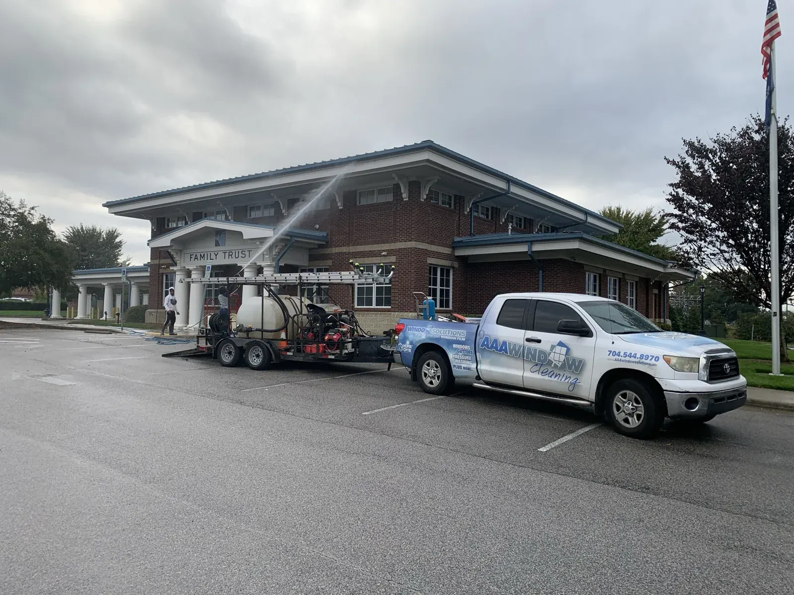 Commercial exterior-cleaning crew working outside a brick building