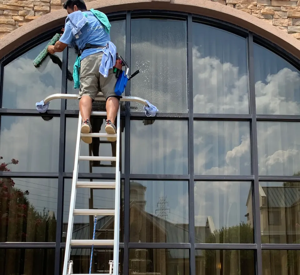 A service-family crew member hand-cleaning a large exterior window